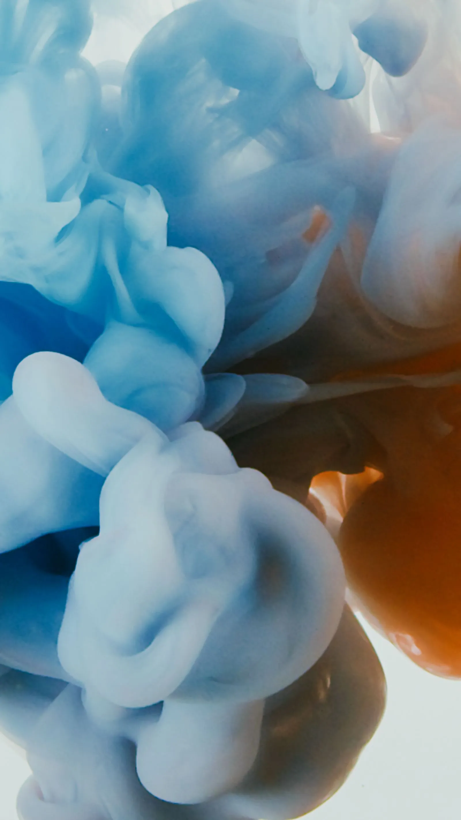 Blue and amber ink clouding through a clear liquid as it disperses