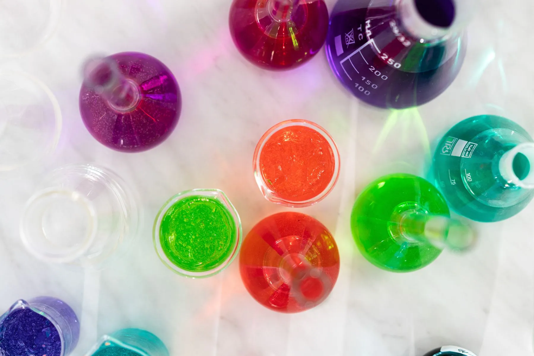 Flasks of coloured solutions on a marble bench, seen from above